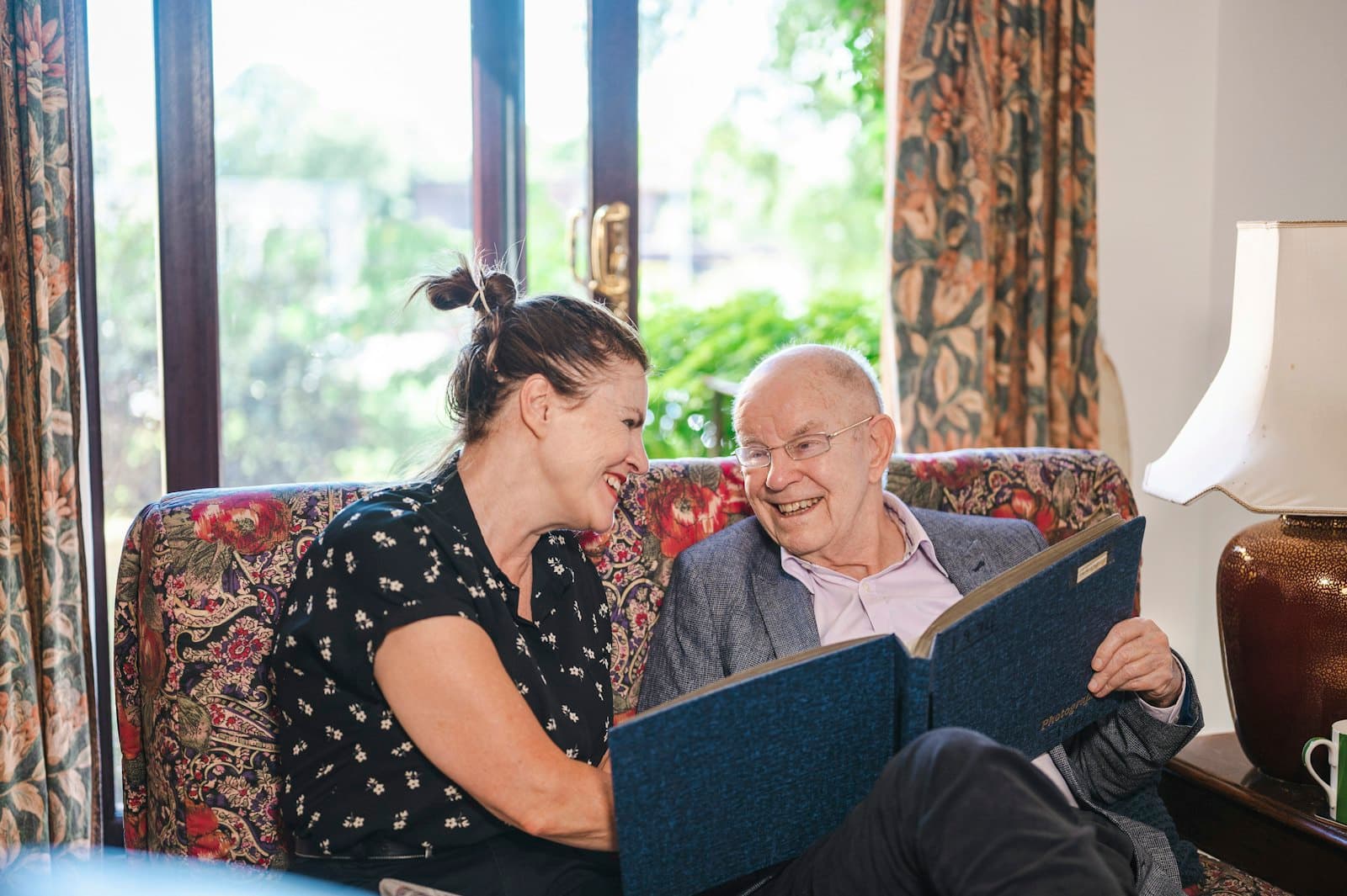 A daughter laughing with her father over a photo album at home