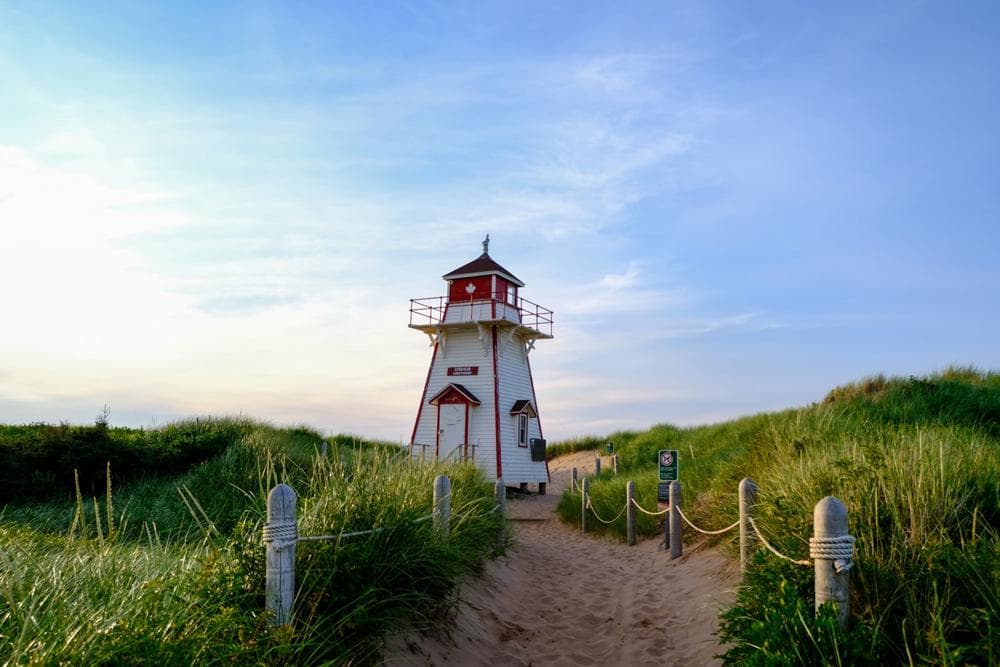 A red and white lighthouse on a PEI beach